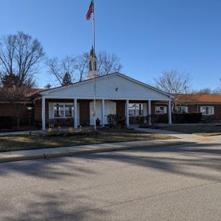 A community center with an American flag flying in front, set against a clear blue sky.