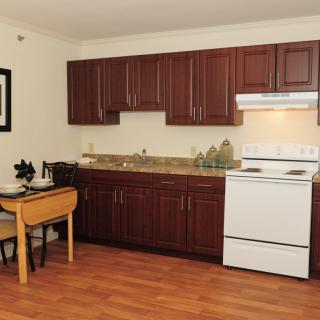 A compact kitchen with wooden cabinets, a white stove, and a small dining table.