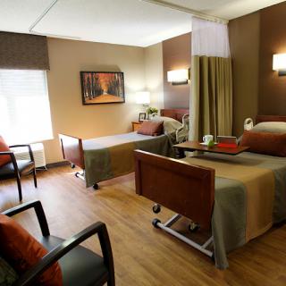 A well-equipped hospital room with two beds and comfortable seating.