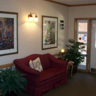 A cozy living room with a red sofa, indoor plants, and framed artwork on the walls.