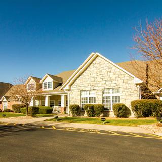 A suburban residential house with a stone facade under a clear blue sky.