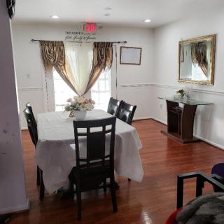 A cozy dining room with a table and chairs, decorated with elegant curtains and a mirror on the wall.