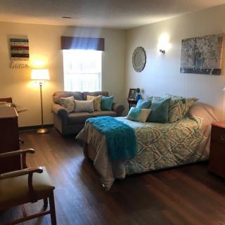 A cozy bedroom with a comfortable bed, sofa, and warm lighting.