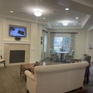 A cozy living room with a fireplace and seating area, featuring a television mounted above the mantle.
