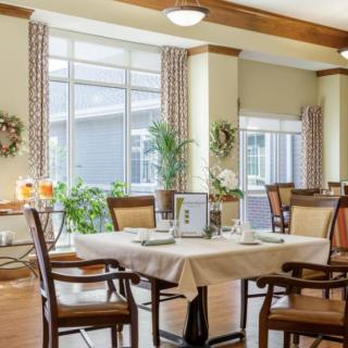A well-lit dining room with elegant furniture and decorative plants.