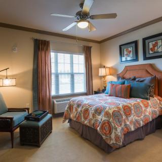 A cozy bedroom with a neatly made bed, decorative pillows, and warm lighting.