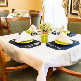 A neatly set dining table with elegant place settings, including folded napkins and a floral centerpiece.