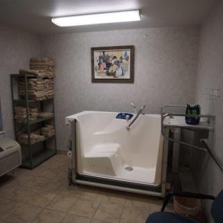 A modern bathroom with a walk-in bathtub and neatly stacked towels.