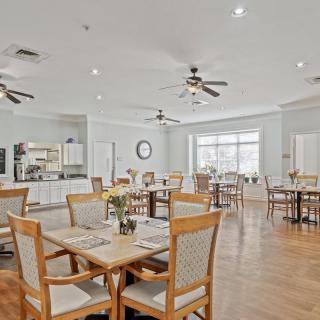 A spacious dining area featuring wooden tables and chairs, with ceiling fans and bright lighting.