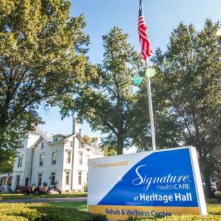 A sunny day at the Signature Healthcare facility with a visible sign and American flag.