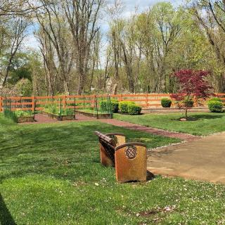 A peaceful park scene with a bench overlooking a pathway and surrounding trees.