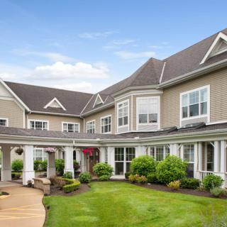 A view of a large suburban house with a landscaped garden and lawn.