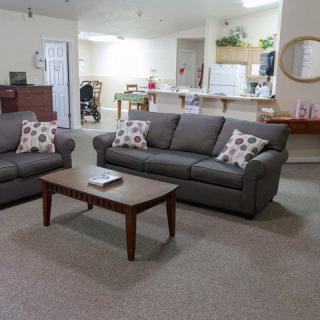 A cozy living room with two gray sofas, a wooden coffee table, and an open view of the kitchen area.
