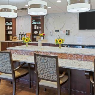 A modern kitchen area with a decorative counter, chairs, and sunflowers.