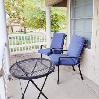 A cozy patio with two blue cushioned chairs and a small round table, ideal for relaxation.