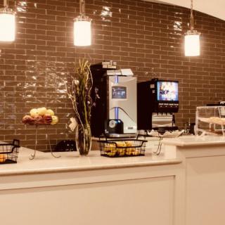 A cozy coffee shop counter with a beverage machine, snacks, and warm lighting.
