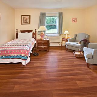 A cozy bedroom with a single bed, wooden floors, and a comfortable armchair.