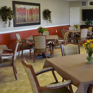 A cozy dining area with tables and chairs, decorated with flowers and artwork.