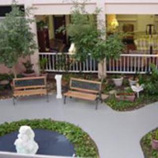 A peaceful garden with benches, a fountain, and greenery.