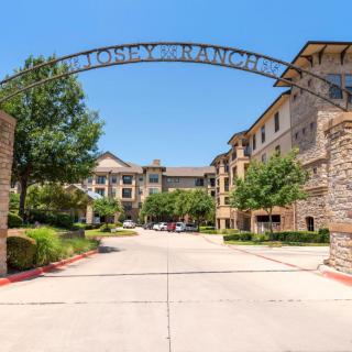 Entrance to an apartment complex with a decorative archway and surrounding landscaping.