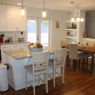 Modern kitchen and dining area with white cabinets and wood flooring.