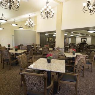 Elegant dining area with chandeliers and neatly arranged tables and chairs.