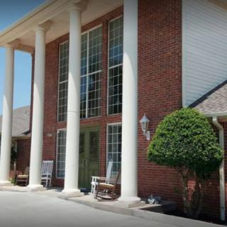 A brick building with large windows and white columns at the entrance.