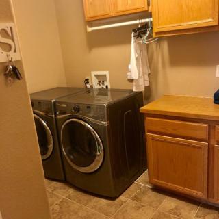 A laundry room with a washer, dryer, and wooden cabinets.