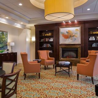 A cozy living room with a central fireplace, surrounded by armchairs and bookshelves, featuring elegant decor.