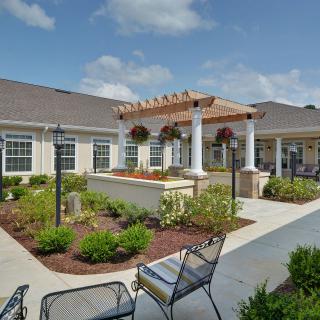 A beautifully landscaped courtyard with outdoor seating and a pergola on a sunny day.