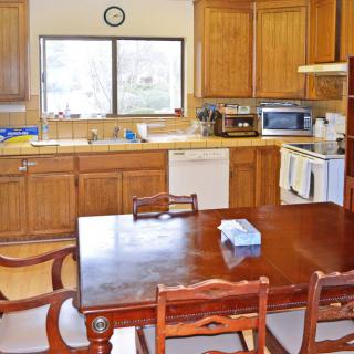 A spacious kitchen with wooden cabinets and a dining table set for meals.