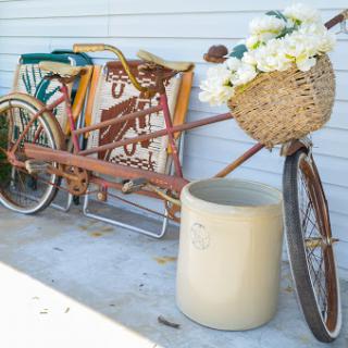 A charming vintage bicycle adorned with a woven basket of flowers, adding a touch of rustic beauty to the outdoor setting.