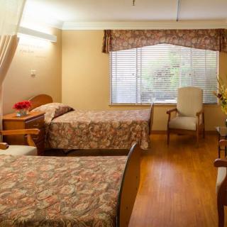 A cozy bedroom with twin beds, a chair, and a window with curtains.