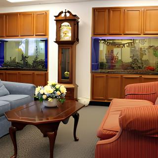 A cozy living room featuring a grandfather clock, aquariums, and comfortable seating.