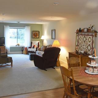 A cozy and inviting living room with a dining area, featuring comfortable seating and warm lighting.