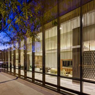 A modern building featuring a sleek glass facade, showcasing its stylish interior illuminated during the evening.
