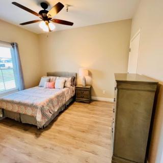 A modern bedroom with a comfortable bed, dresser, and ceiling fan.