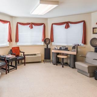 A retro-style salon interior with chairs and hair dryers, accented by red curtains on the windows.