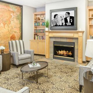 A modern living room featuring a fireplace, comfortable seating, and a television mounted above the mantel.