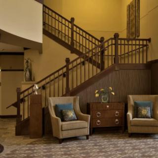 A cozy lobby interior featuring a staircase, comfortable chairs, and elegant decor.