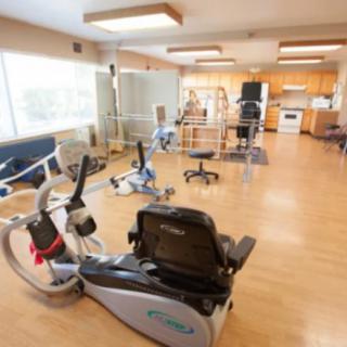 A spacious rehabilitation room equipped with various exercise machines and therapy equipment.