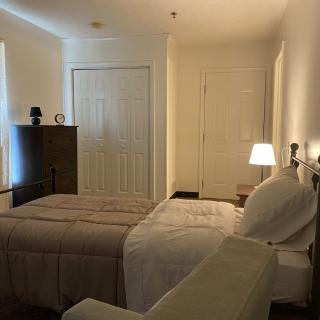 A cozy bedroom with a bed, lamp, and closet.