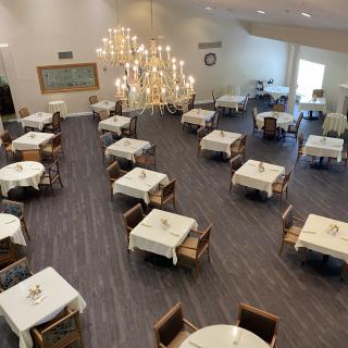An elegant dining area featuring neatly arranged tables and chairs under a large chandelier.