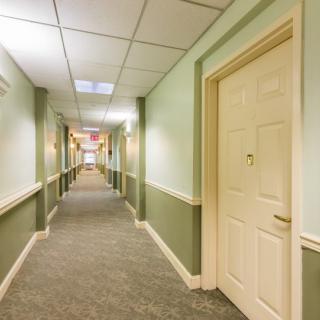 A well-lit hallway with carpeted floors and several doors lining the walls.