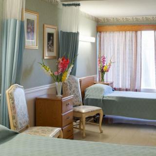 A neatly arranged hotel room with twin beds, elegant furniture, and floral decorations.