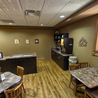 A cozy break room with a kitchen area featuring tables, chairs, a coffee machine, and a microwave.