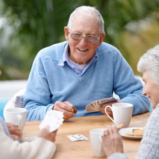 A group of elderly people enjoying a game of cards together outdoors.