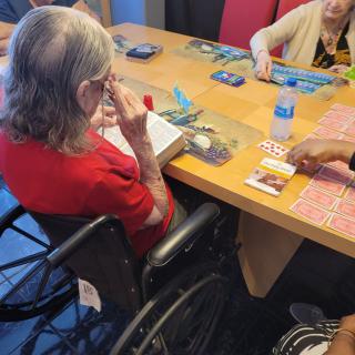 Elderly individuals engaged in a card game around a table.