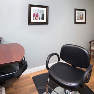 A modern hair salon with a styling chair and framed pictures on the wall.