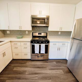 A modern kitchen featuring white cabinetry and stainless steel appliances.